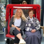 Eine Dame mittleren Alters und eine ältere Frau sitzen im Flaniermobil.