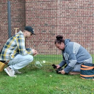 Der Mitarbeiter Xavier Freitag pflanzt mit der Bewohnerin Yvonne gemeinsam eine Himbeerpflanze.