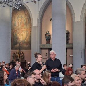 Viele sind zum Tag der Wohnungslosen in die Citykirche gekommen. Eine Frau ist aufgestanden, um eine Frage an das Podium zu richten.