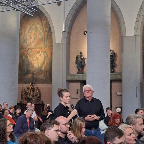 Viele sind zum Tag der Wohnungslosen in die Citykirche gekommen. Eine Frau ist aufgestanden, um eine Frage an das Podium zu richten.