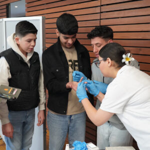 Eine Praxisanleiterin zeigt den Schülern ein paar pflegerischen Tätigkeiten.