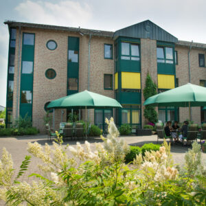 Das Seniorenzentrum St. Anna von Außen. Vor dem Haus stehen grüne Sonnenschirme aufgespannt.