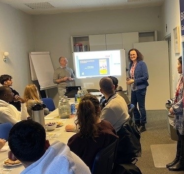 Zugewanderte Jugendlichen sitzen um einen Tisch, schauen auf eine Präsentation und werden von Experten zu Ausbildungschancen im Handwerk informiert.