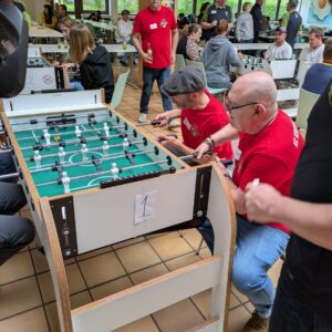 Zwei Männer sitzen am Kickertisch und kickern.