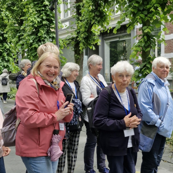 Gut gelaunte Menschen schlendern durch Valkenburg und lächeln in die Kamera.