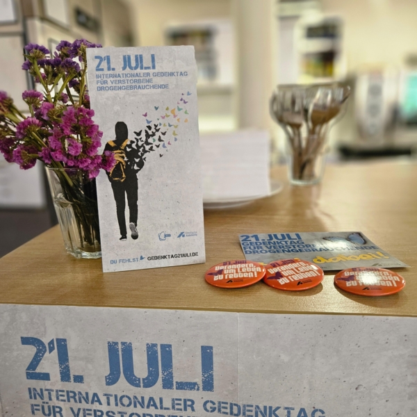 Auf der Theke im Kiosk Troddwar erinnern ein Plakat und Flyer an den Gedenktag verstorbener Drogenabhängiger.