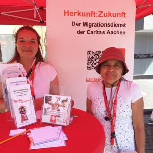 Zwei Caritas-Kolleginnen stehen am Infostand mit Flyern und informieren zu Angeboten der Migration & Integration.