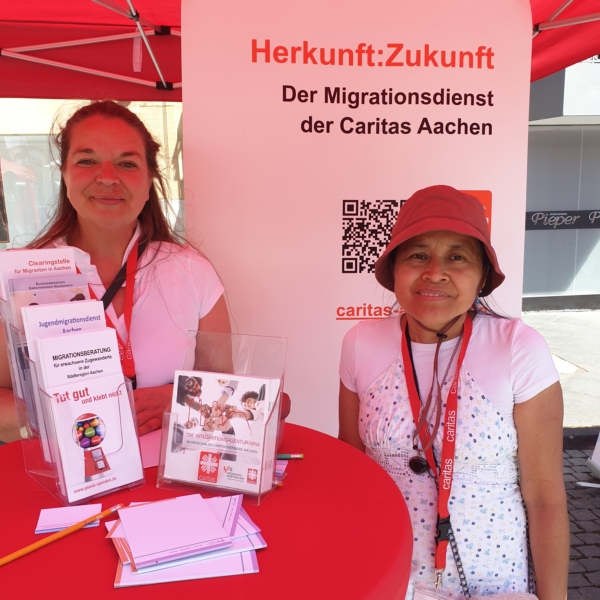 Zwei Caritas-Kolleginnen stehen am Infostand mit Flyern und informieren zu Angeboten der Migration & Integration.