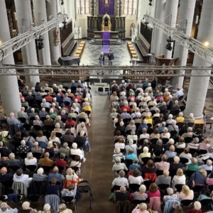 Von der Empore aufgenommenes Bild zeigt die Citykirche mit vollbesetzten Stuhlreihen. Unsere Kollegen stehen vor dem Altar und begrüßen die Gäste.